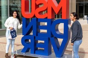 在乔丹学生成功大楼外，两名学生站在一个大大的“MSU DENVER”标志旁边.